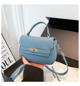 Detail of light blue leather trapezoid bag with gold twist lock and handle in a gift box