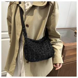 Detail of leopard print crescent crossbody bag showing fabric texture and adjustable strap