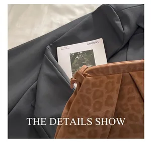 Detail of brown leopard print bag with ruched texture on grey blazer and magazine