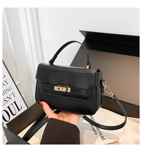 Detail of black leather saddle bag featuring a polished metal clasp and top handle