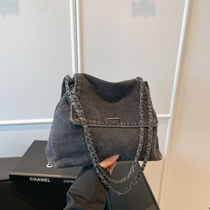 Detailansicht der dunklen Denim-Textur und des Metallkettenriemens an einer Tragetasche