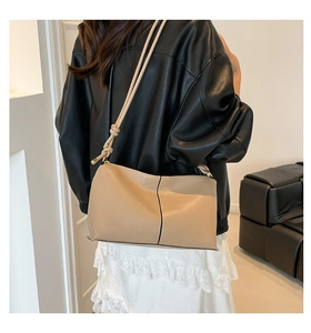 Detail of beige leather shoulder bag featuring black vertical stitching and sleek straps