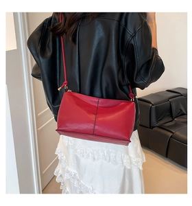 Model wearing a vintage red leather crossbody bag with adjustable gold buckle details