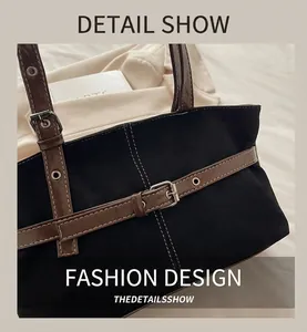 Close-up of black tote bag featuring brown leather straps and silver metal buckles