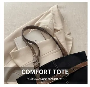 Detail of black large-capacity tote bag with white stitching and brown leather strap