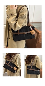 Detail of black canvas tote bag with brown leather straps and a plush bear charm on a shoulder bag
