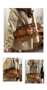 Detail view of brown suede tote bag with leather straps and cute bear pendant charm