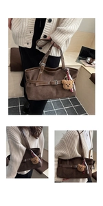 Detail view of brown suede tote bag with metal buckle and cute teddy bear pendant
