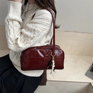 Bolso bandolera retro burdeos de cuero con borla de cuentas en un ambiente otoñal