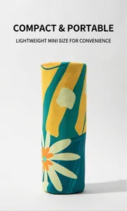 Detail of rolled large sand-free beach towel with bright daisy and geometric prints