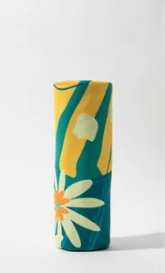 Detail of rolled large sand-free beach towel with bright daisy and geometric prints