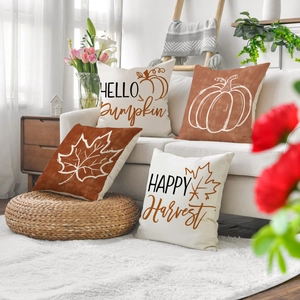 Set of four autumn pumpkin and maple leaf linen pillow covers on a white sofa