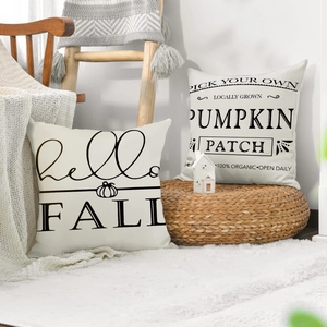 Detail of linen pumpkin pillow covers with hello FALL print on a cozy wooden chair