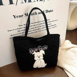 Detail of heart quilting and cute cartoon dog patch on black soft fabric tote bag