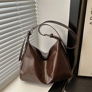 Retro deep brown faux leather hobo tote bag with adjustable strap in natural window light