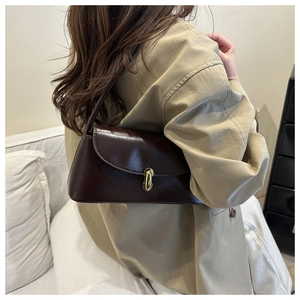 Detail of a minimalist dark brown leather underarm bag with a gold metallic twist lock