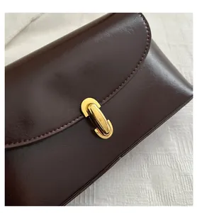 Close-up of the vintage brown leather flap and golden metallic square buckle detail