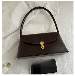 Detail shot showing the compact size of a brown vintage leather bag next to a smartphone