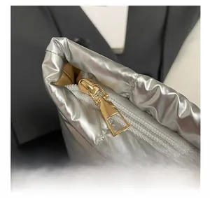 Macro detail of silver quilted fabric texture and premium gold zipper on the square bag