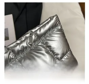 Detailed close-up of metallic silver quilted fabric with shiny finish and grid texture