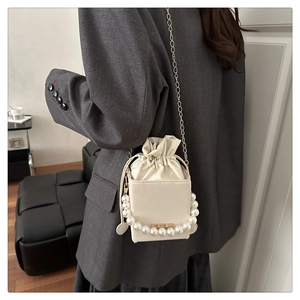 Detail der weißen Lederbox-Tasche mit Perlengriff und goldener Kette am Model