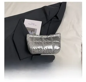 Detail of silver quilted pouch with square stitching next to a dark blazer and books
