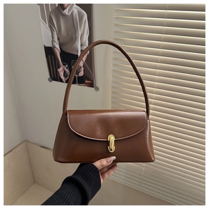 Detail of a dark brown PU leather underarm bag with an elegant golden oval metal clasp