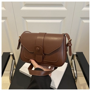 Detail of dark brown leather crossbody bag with vintage flap and golden hardware
