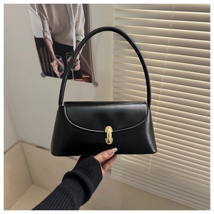 Detail of black glossy faux leather baguette bag with a gold metal capsule buckle clasp