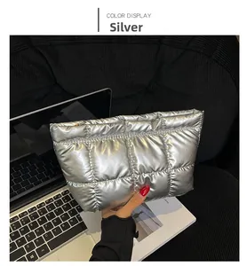 Close-up of a silver quilted puffer pouch with metallic finish held by hand
