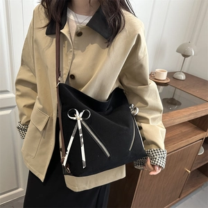 Black canvas tote bag with metal zippers and leopard bow ribbon on model shoulder