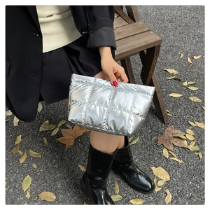 Chic silver quilted clutch bag with metallic finish shown in a stylish outdoor setting