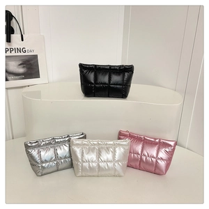 Metallic quilted makeup bags in black, silver, white, and pink on a white display stand