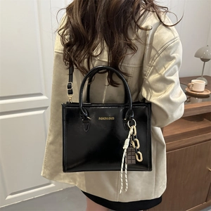 Sac à main en cuir noir brillant avec lettrage doré et bandoulière réglable