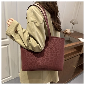 Close-up of the vintage leopard print pattern on a large burgundy tote bag shoulder strap