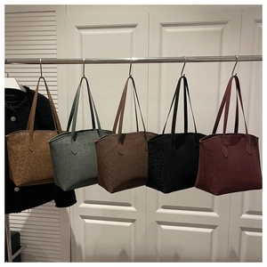Multiple colors of leopard print suede tote bags hanging on a display rack for selection