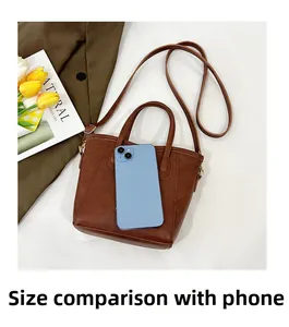 Size comparison of a dark brown leather tote bag with a smartphone on white background