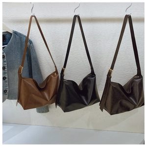 Three hobo bags in black, brown, and coffee hanging on hooks with a denim jacket
