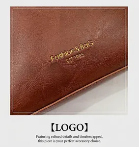 Detail of brown litchi grain leather bag with embossed golden Fashion & Bag logo