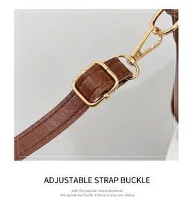 Detail of brown leather strap with gold metal buckle and hook on a stylish bucket bag