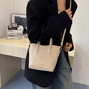 Beige faux leather tote bag with gold lettering shown on a model for casual daily style