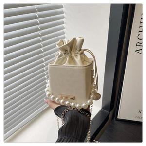 Detail der cremeweißen Beuteltasche mit großem Perlengriff und goldener Kette