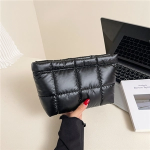 Minimalist black quilted puffer cosmetic bag with soft puffy checkered texture held in hand