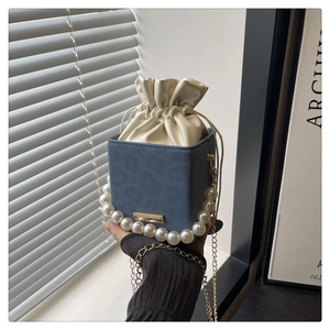 Detailansicht der nebelblauen quadratischen Tasche mit Perlengriff und Goldkette