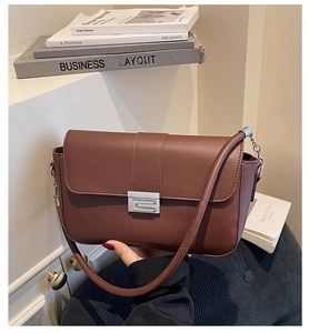 Brown leather shoulder bag featuring modern silver buckle and metal chain strap detail
