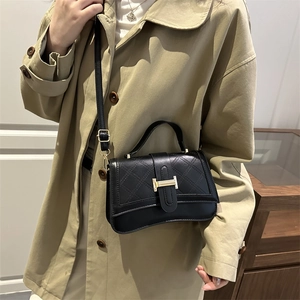 Schwarze Stepptasche mit goldener H-Schnalle kombiniert mit einem khakifarbenen Trenchcoat