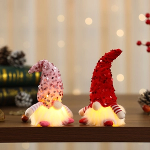 Pair of glowing Christmas Gnomes with red and purple sequin hats on a cozy wooden table