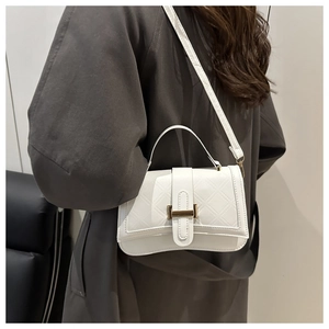 Detail of white quilted crossbody bag with metal buckle and adjustable strap on model