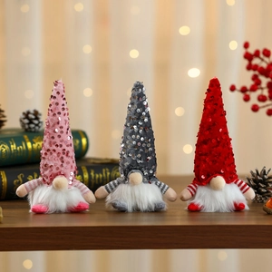 Three sequined holiday faceless gnomes in pink grey and red on a festive wooden surface