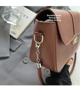 Close-up of durable metal hook and leather strap attachment on a brown baguette bag